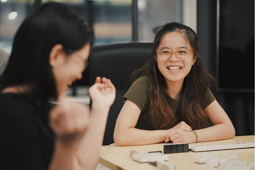 Two women laughing together while playing a board game