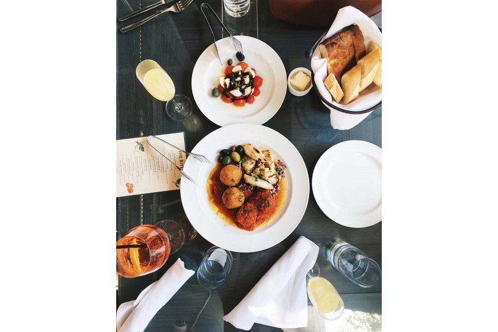 A top-down view of a dinner and dessert meal with white plates