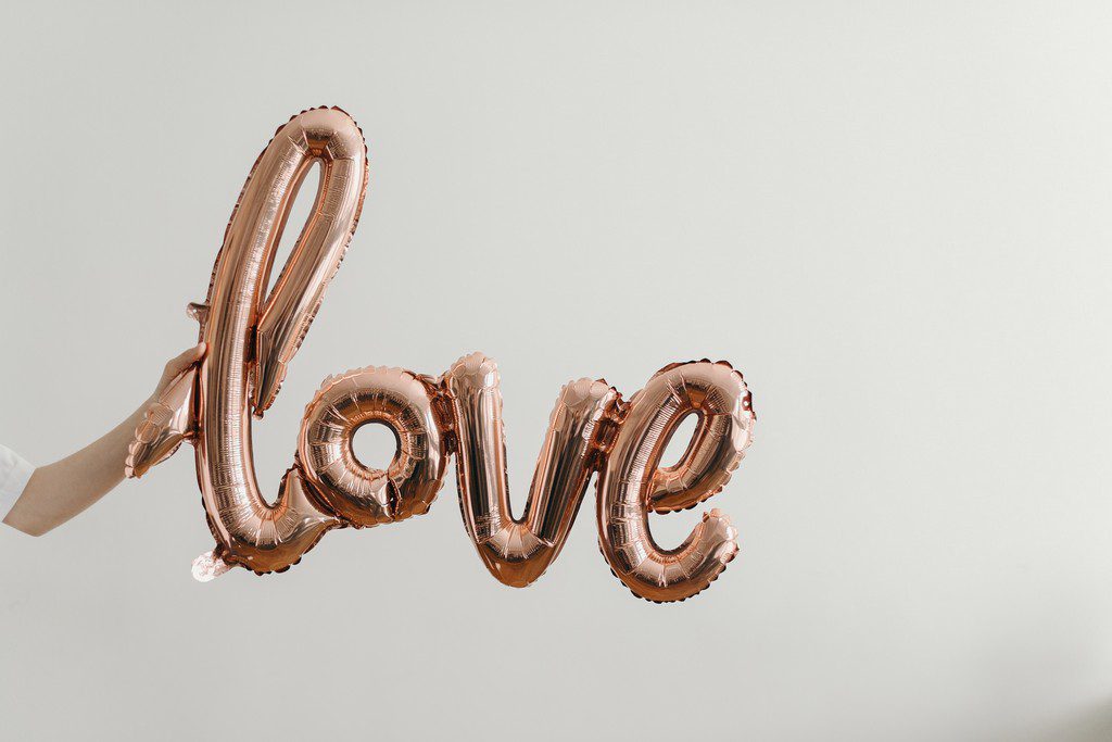 pink chrome balloon shaped like the word "love"