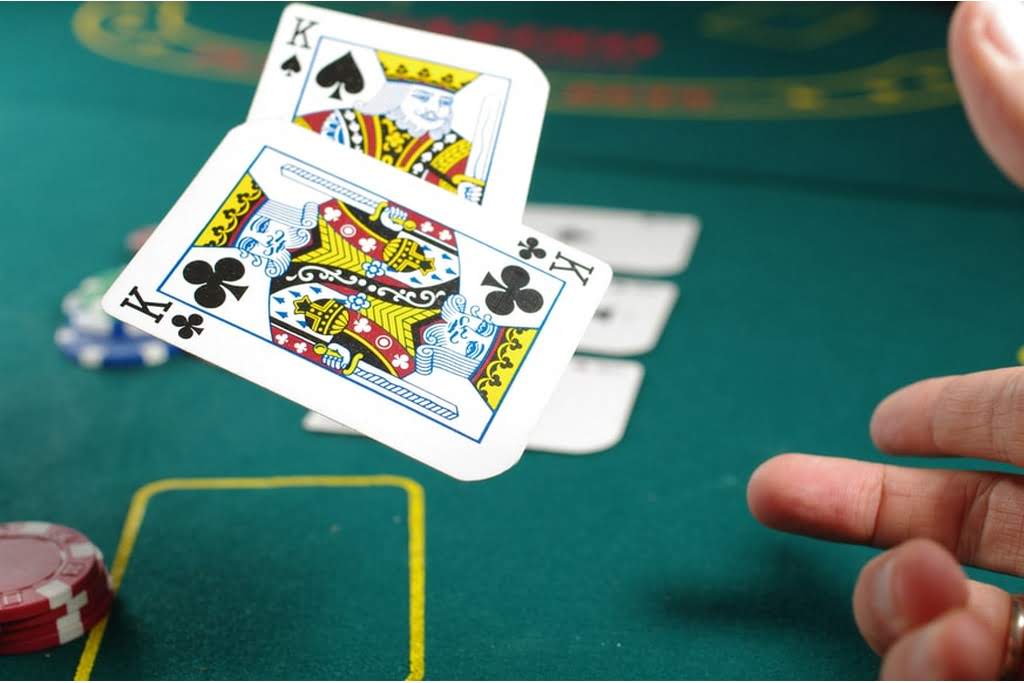 Two playing cards, face up, being tossed onto a casino table