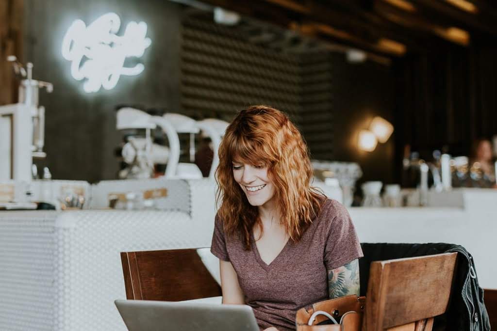 A woman smiling while looking at her laptop