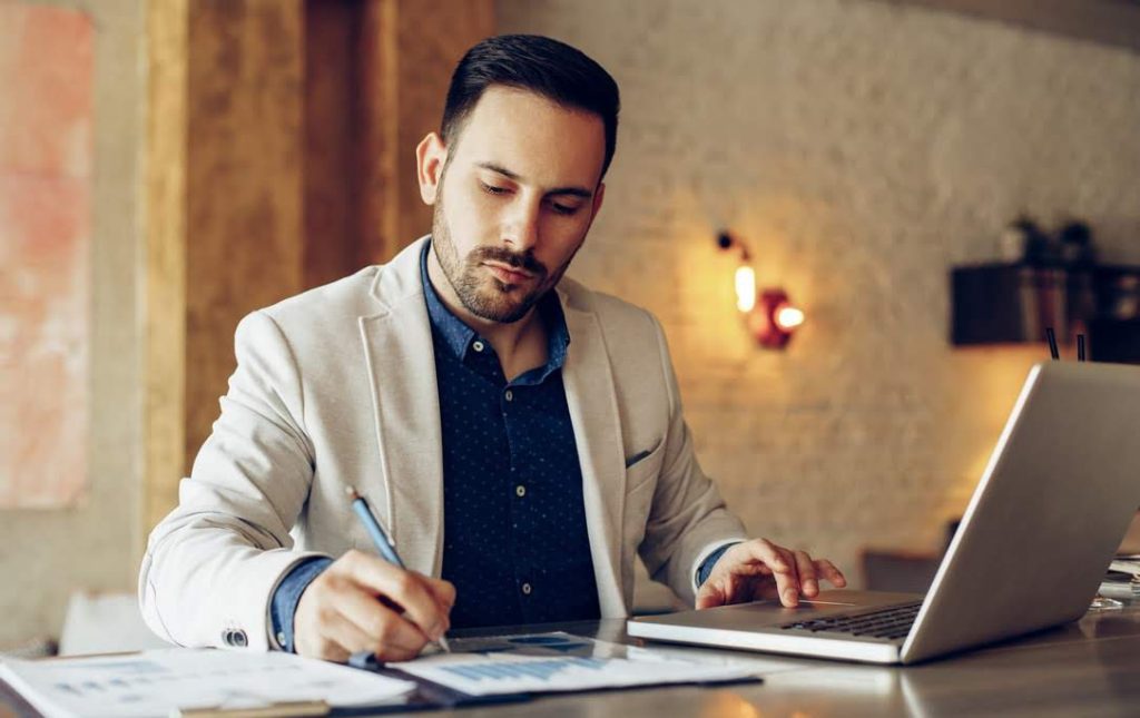 man taking notes from his computer