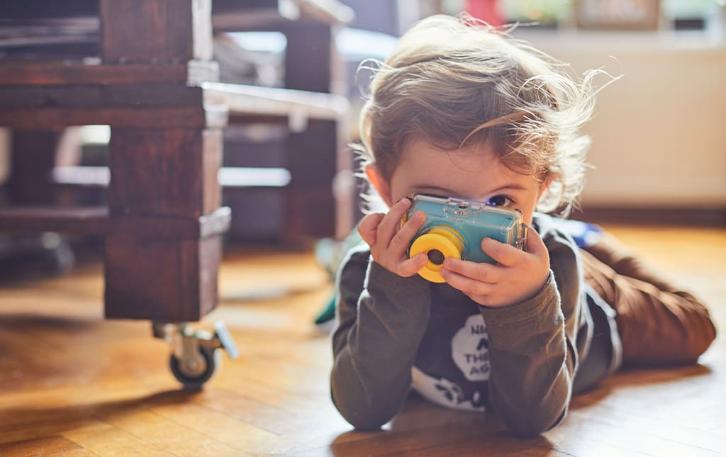 Young pre-school student looking through toy camera