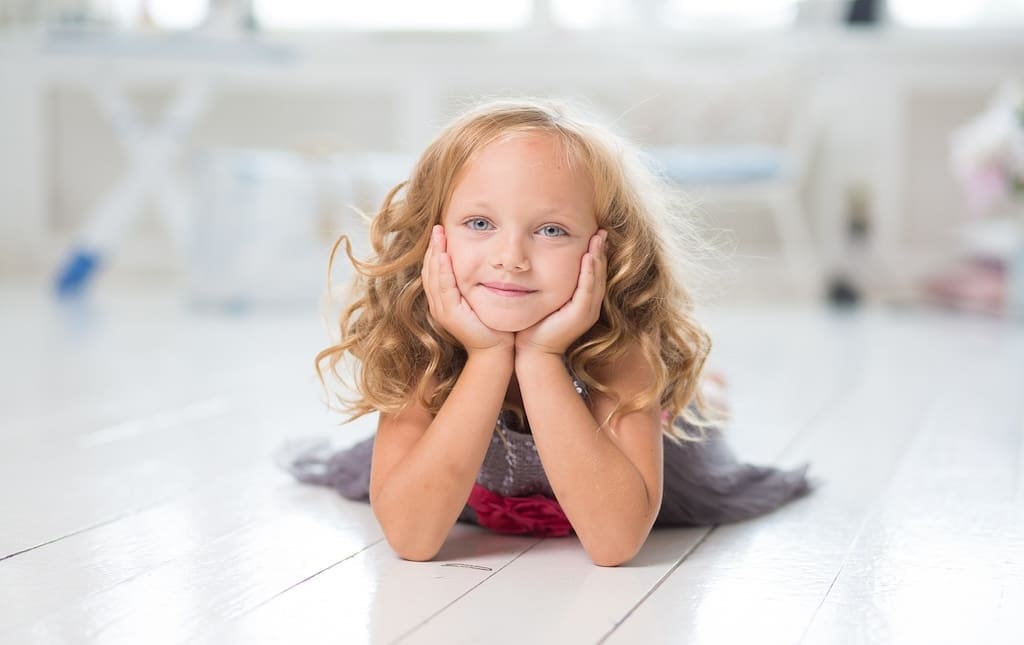 Young girl with her head in her hands smiling for a photo