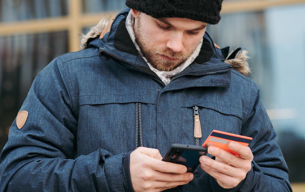 man entering credit card info into phone