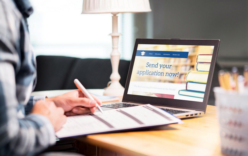 Teacher writing grant application in front of laptop