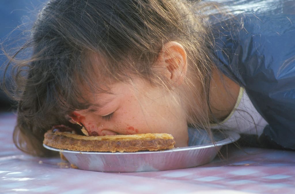 School student participating in pie eating contest school fundraiser