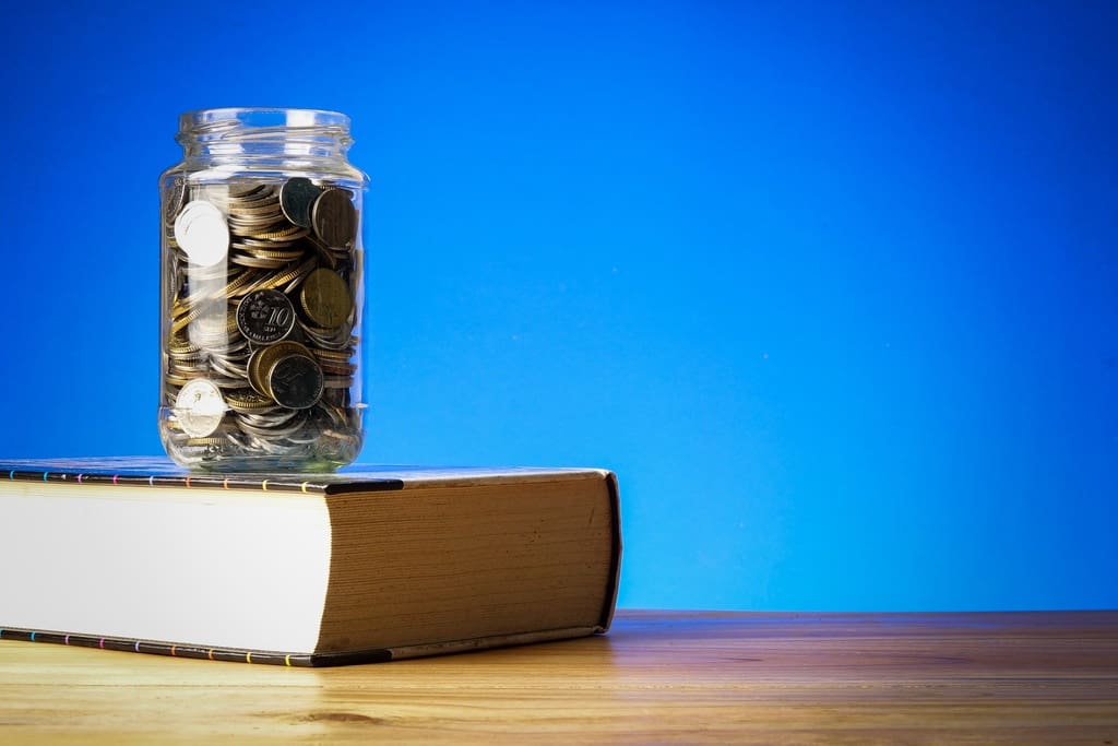 Jar of coins on top of textbook to represent donation campaigns