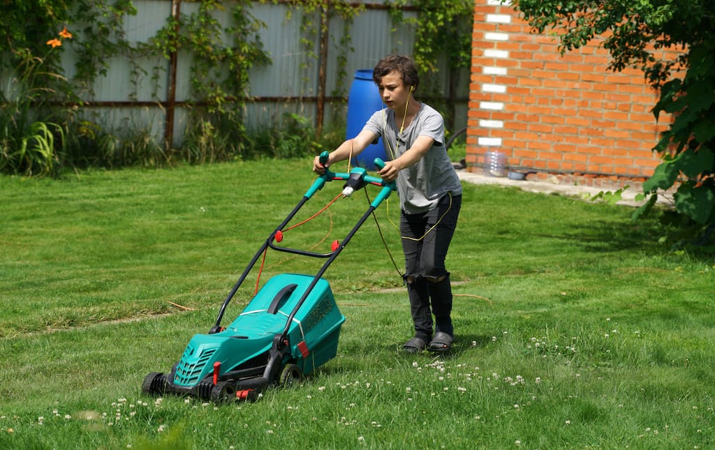 middle school age boy cutting grass