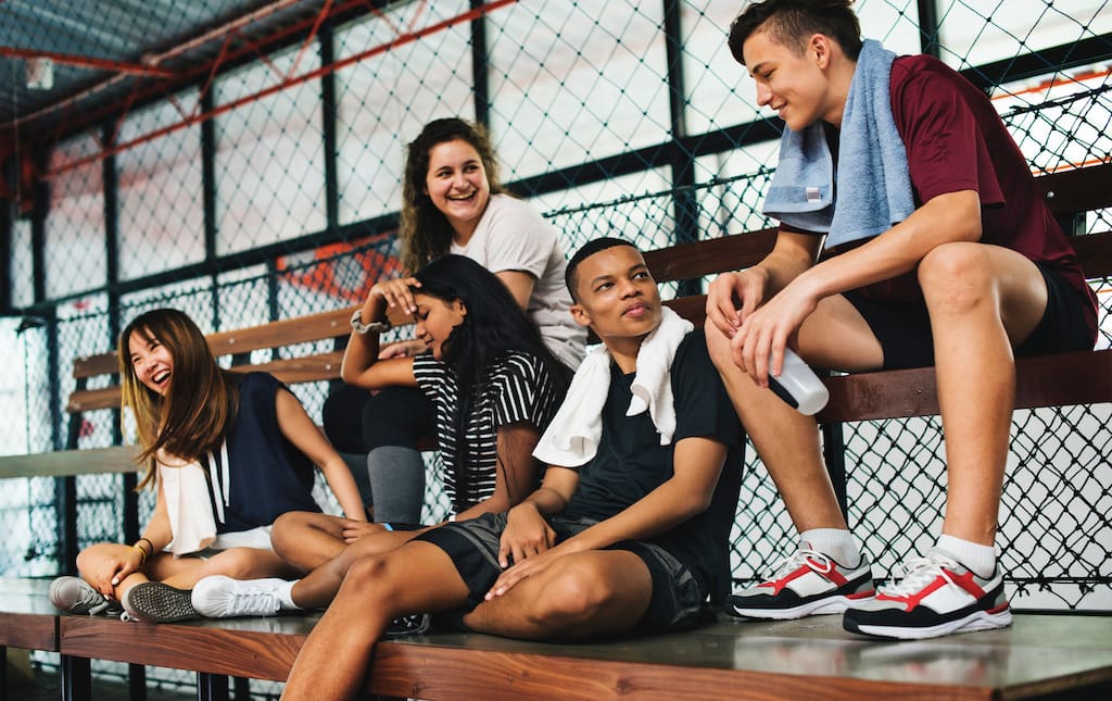 Group of Young People Sitting on Bench with Towels and Water Bottles