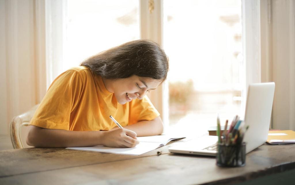 female student writing a letter on paper