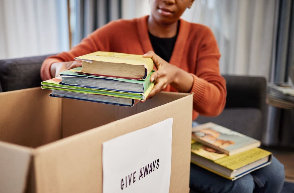 Student placing books in box for classroom library book drive