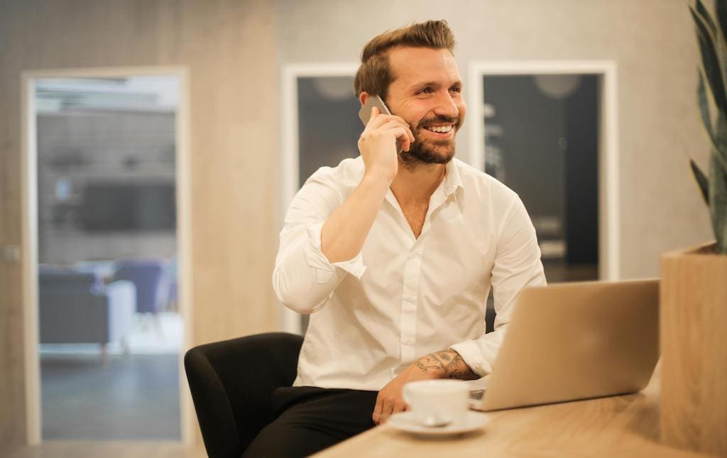 man making a phone call while he's working on laptop