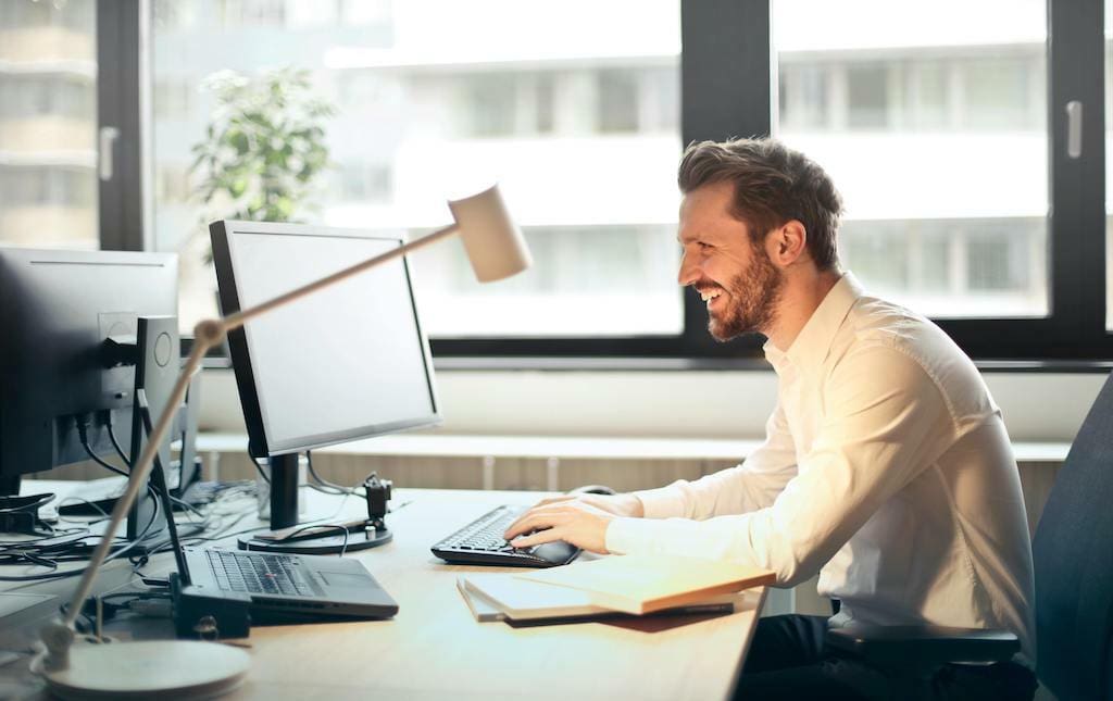 Man sitting at a desk typing emails