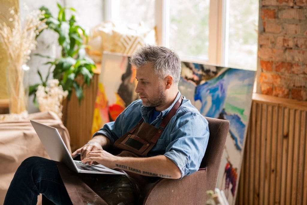 Artist using Patreon for fundraising campaign on laptop in studio