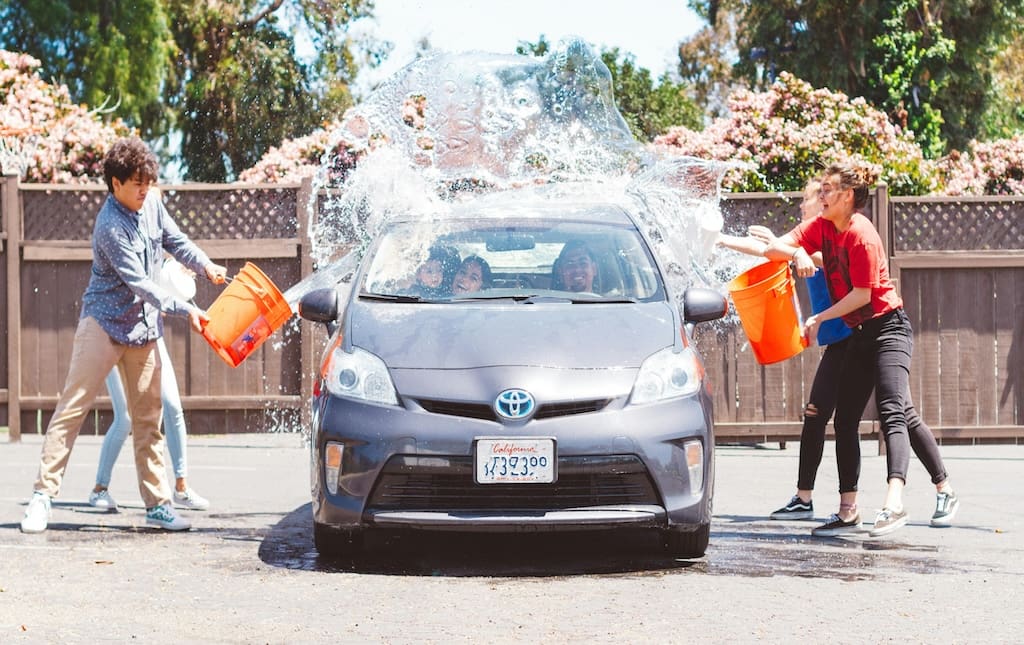 Young kids washing a car outside as part of a fundraising initiative