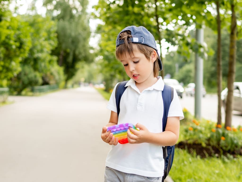 School age child holding cheap plastic toy with lukewarm facial expression