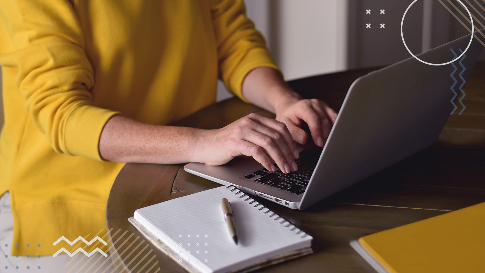Person in yellow sweater working on laptop at table